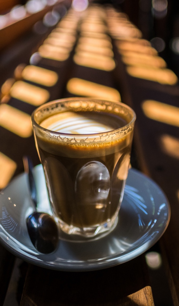 Стакан с кофе стоит на деревянном лавке