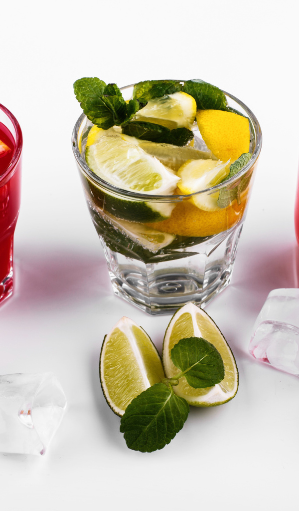 Стаканы с цитрусовыми коктейлями со льдом на белом фоне с фруктами