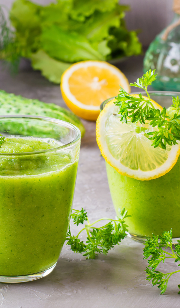 Зеленый смузи в стаканах с кусочками лимона и петрушкой