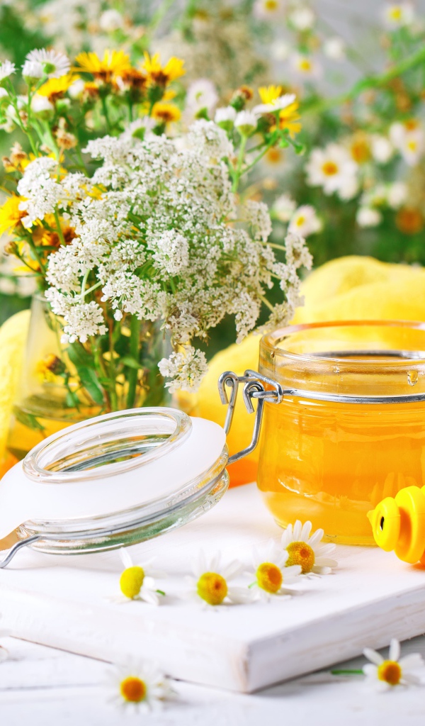 Банка меда на столе с цветами