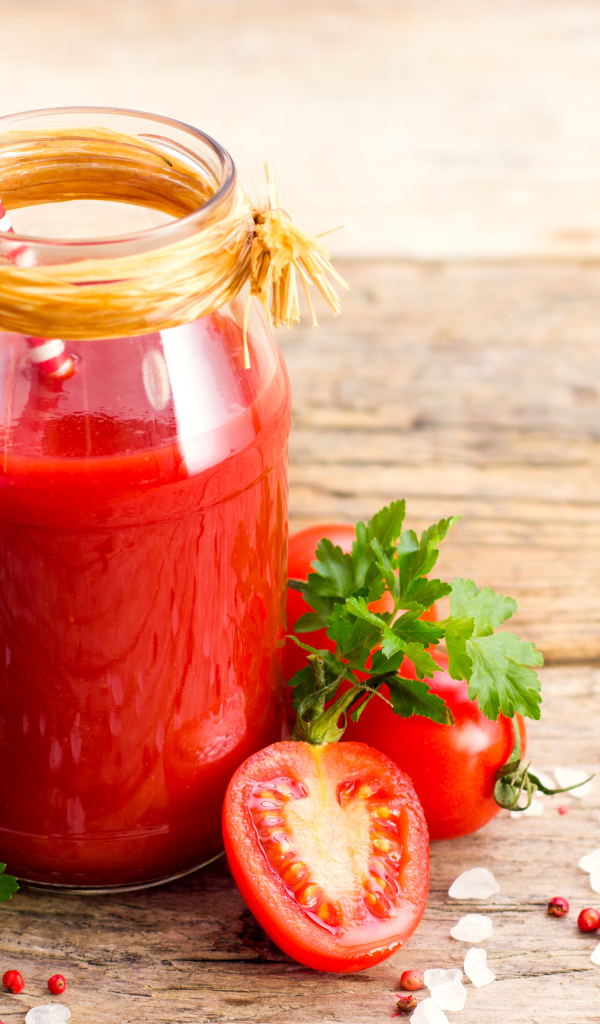 Банка томатного сока на столе с помидорами и петрушкой