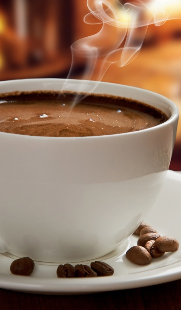 Большая белая чашка с горячим кофе на столе с кофейными зернами