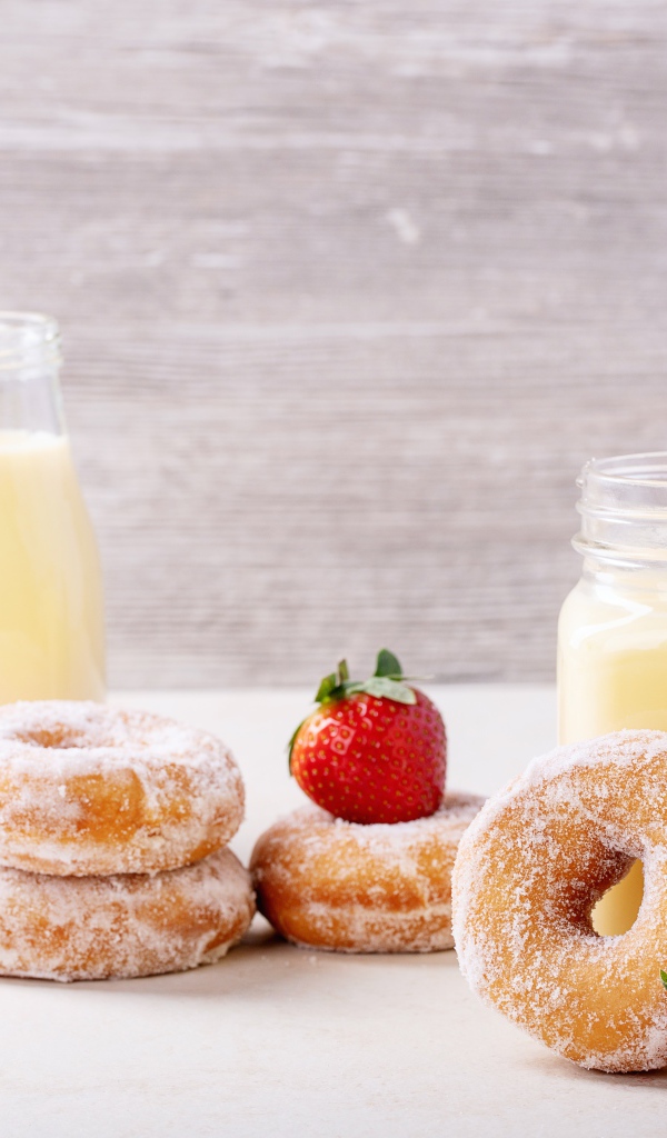 Молочные коктейли на столе с клубникой и пончиками