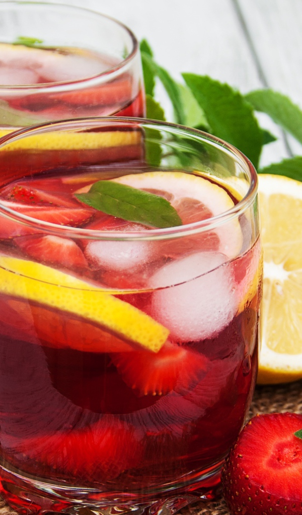 Мохито в стаканах на столе с клубникой, лимоном и мятой