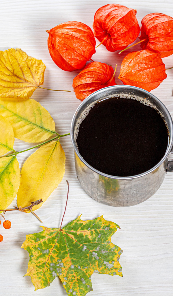 Кружка кофе на столе с осенними листьями, физалисом и шиповником