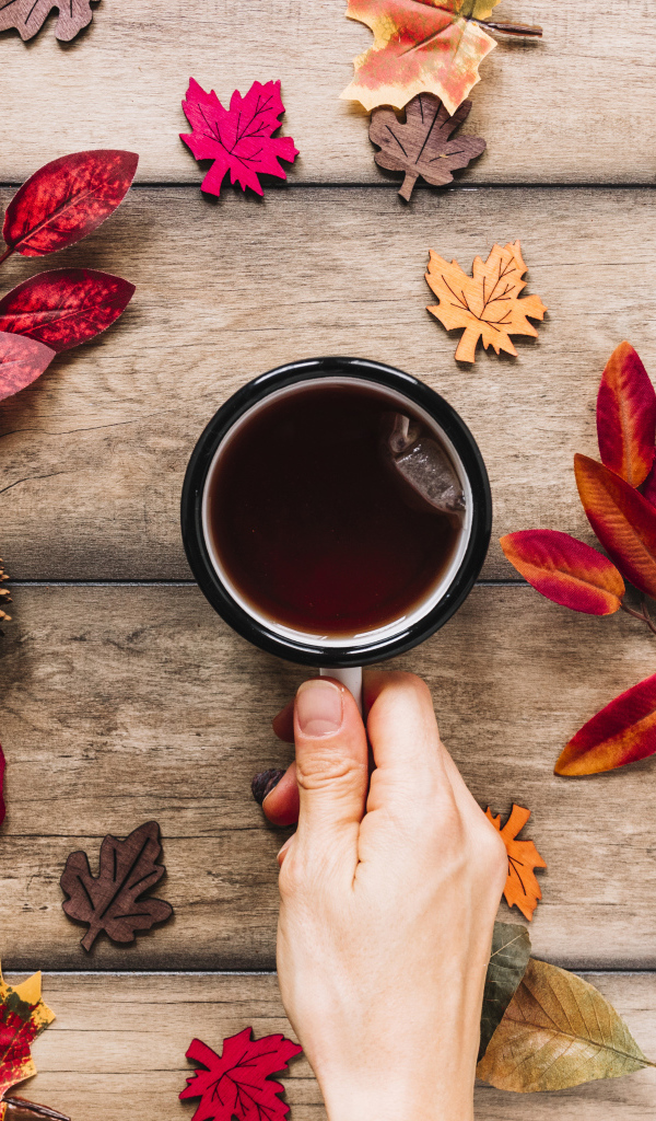 Кружка чая на столе с осенними листьями