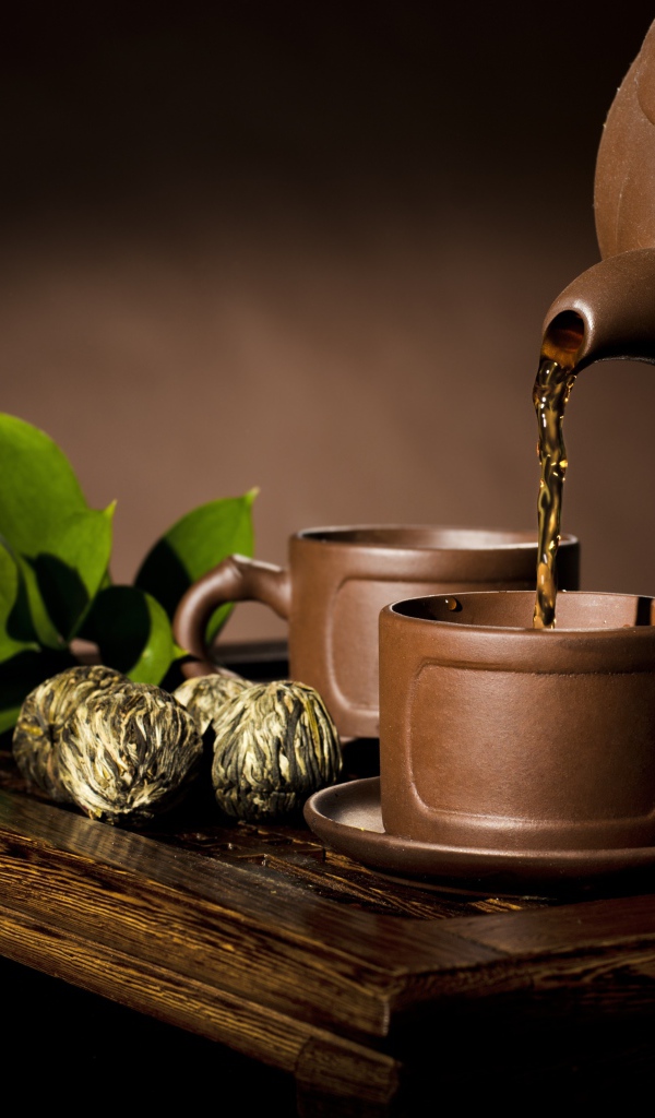 Чай наливают из чайника в коричневую чашку