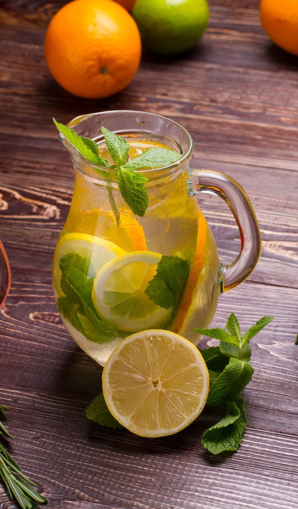 Три стеклянных графина с напитком на деревянном столе с фруктами