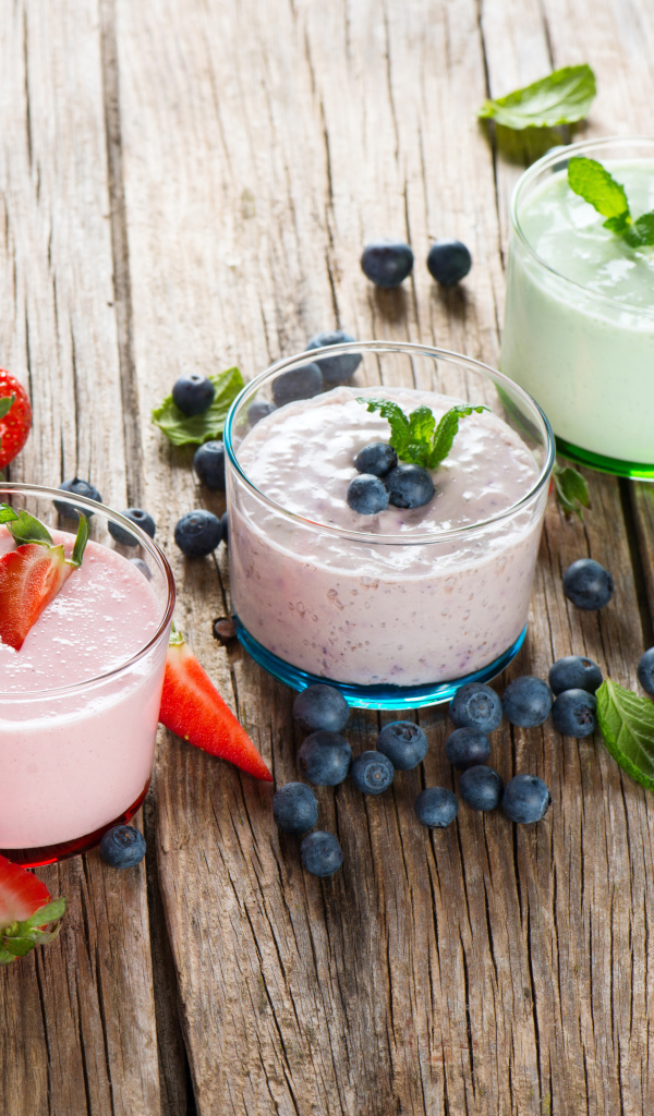 Три стакана смузи с ягодами на деревянном столе