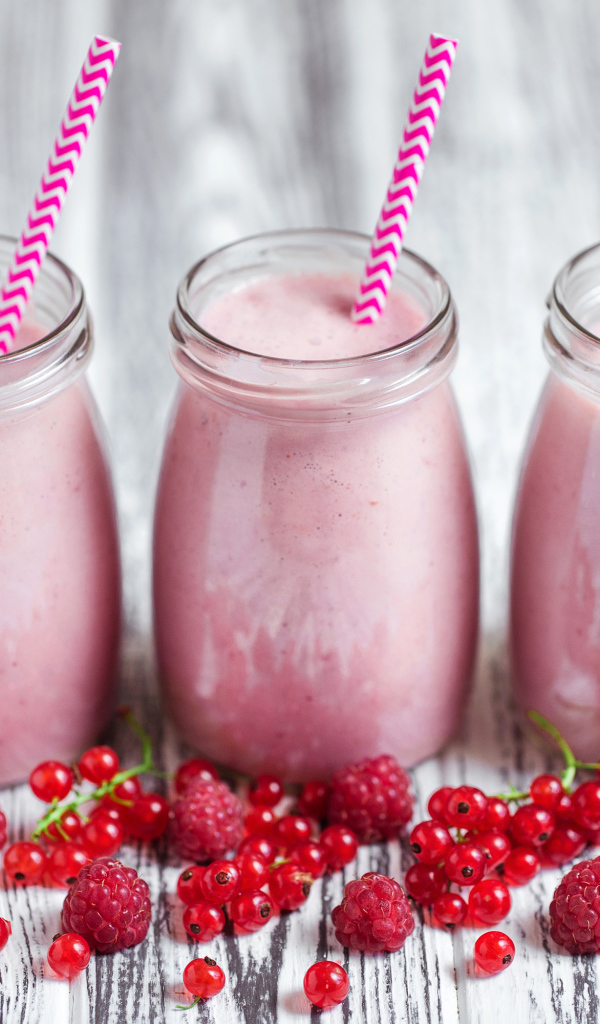 Три банки ягодного  смузи на столе с ягодами малины и смородины