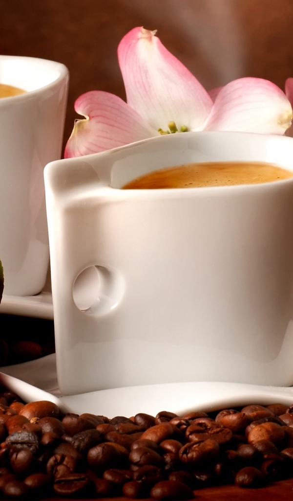 Две чашки кофе на столе с кофейными зернами и цветами