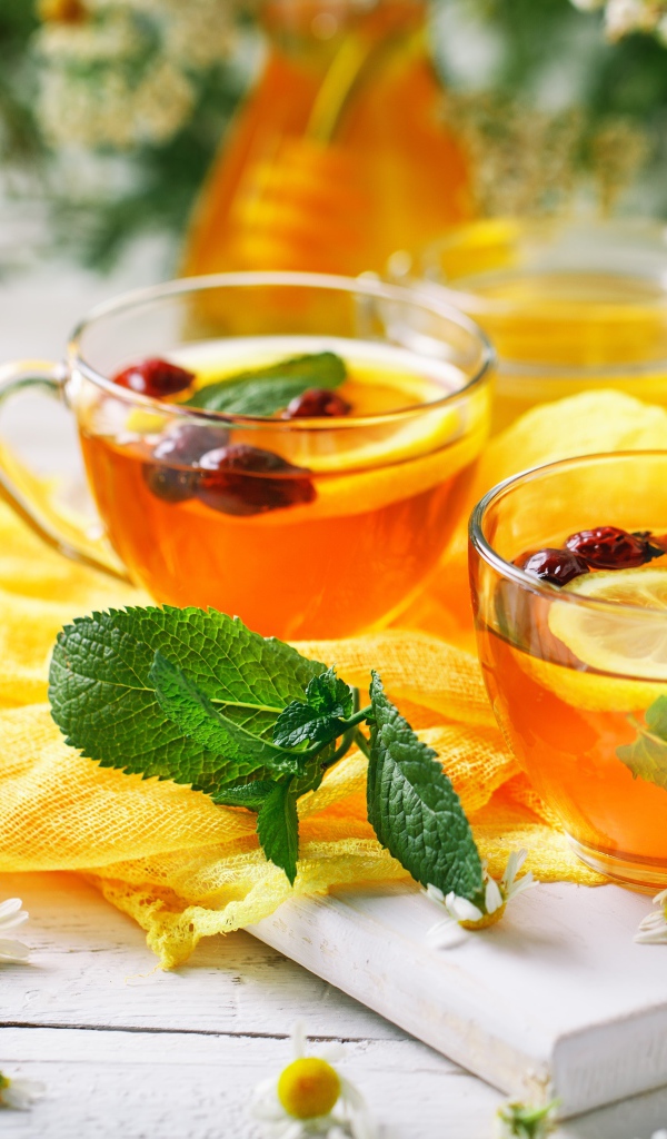 Две стеклянные чашки чая с лимоном, мятой и шиповником