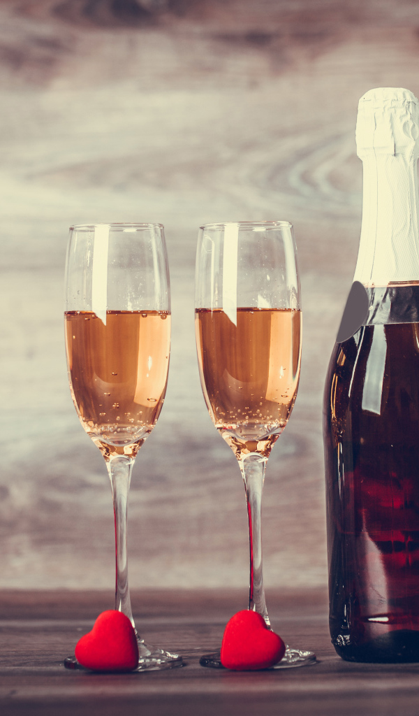 Два бокала и бутылка шампанского на столе с букетом роз