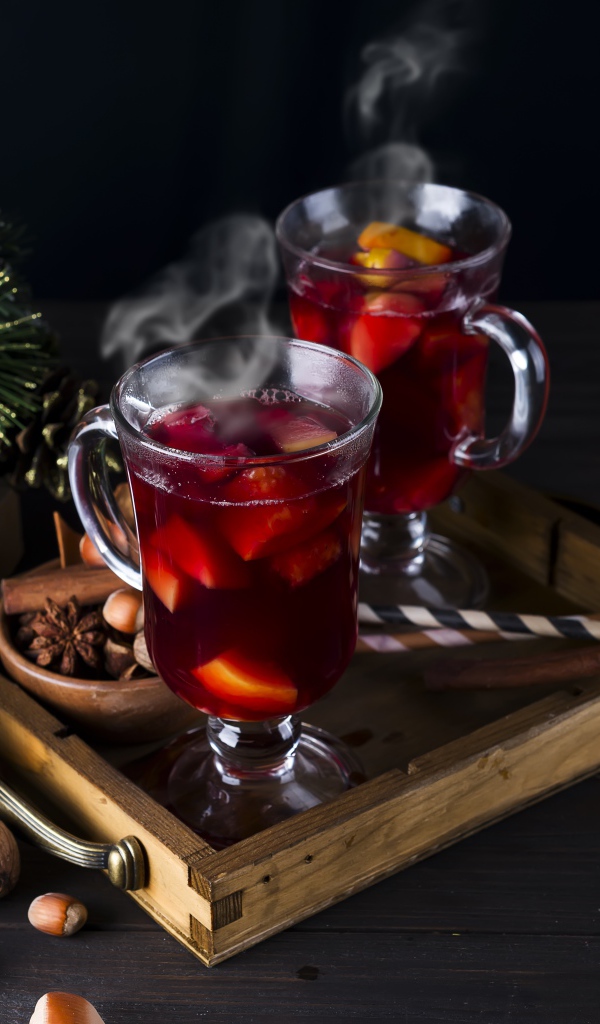 Два стакана горячего глинтвейна на столе с еловой веткой