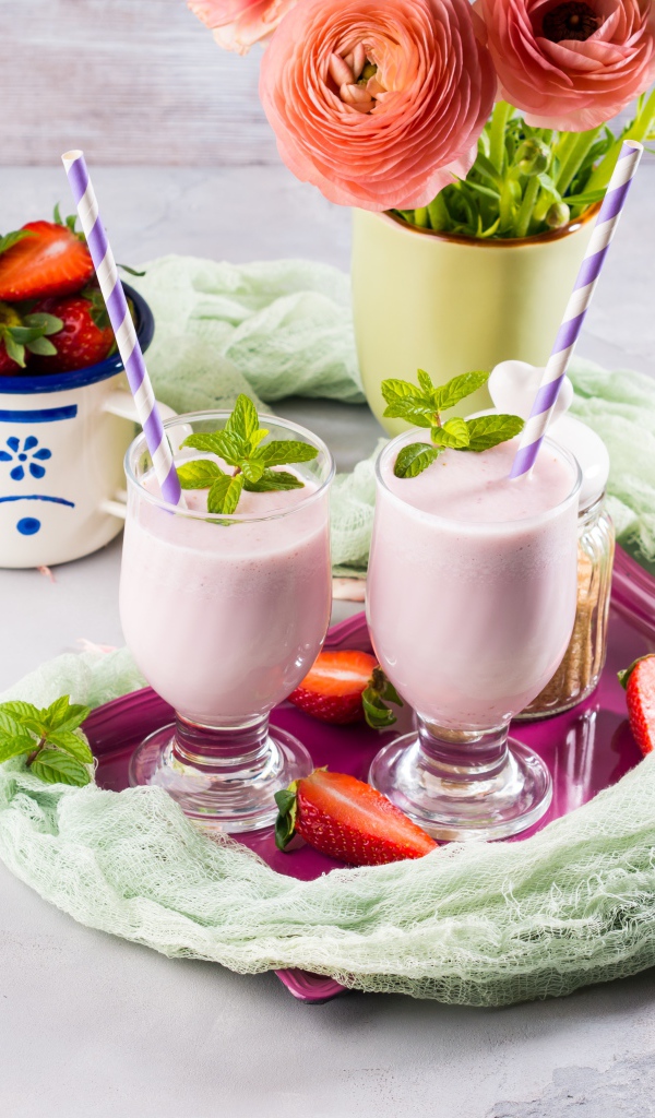 Два стакана с коктейлем на столе с букетом и клубникой