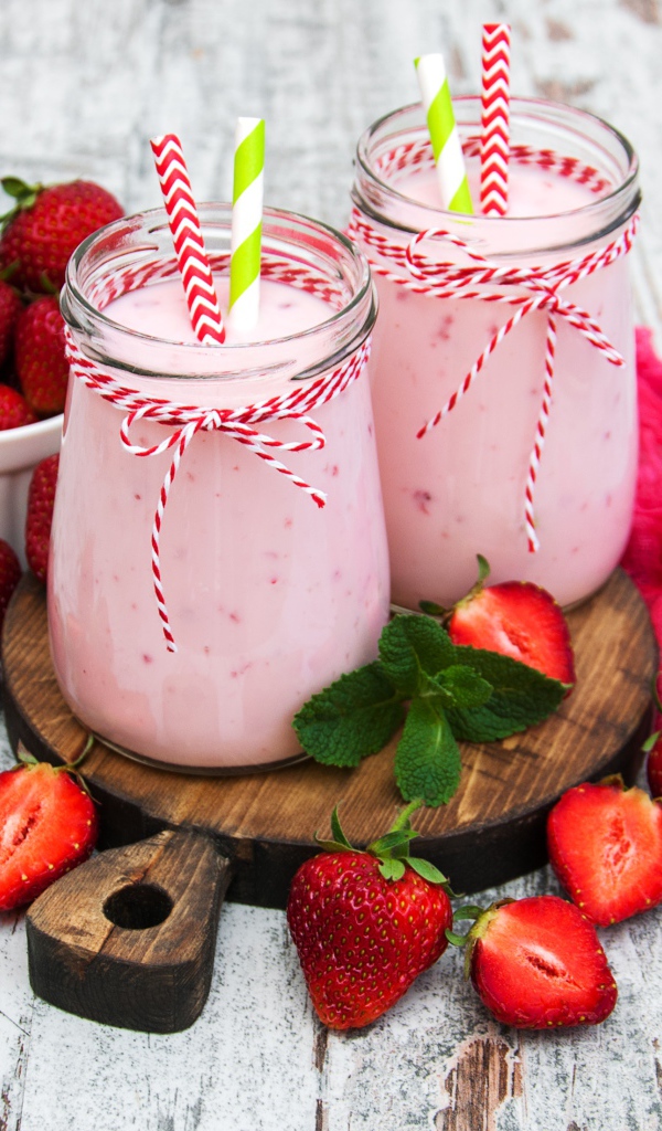 Две банки смузи стоят на доске на столе с клубникой