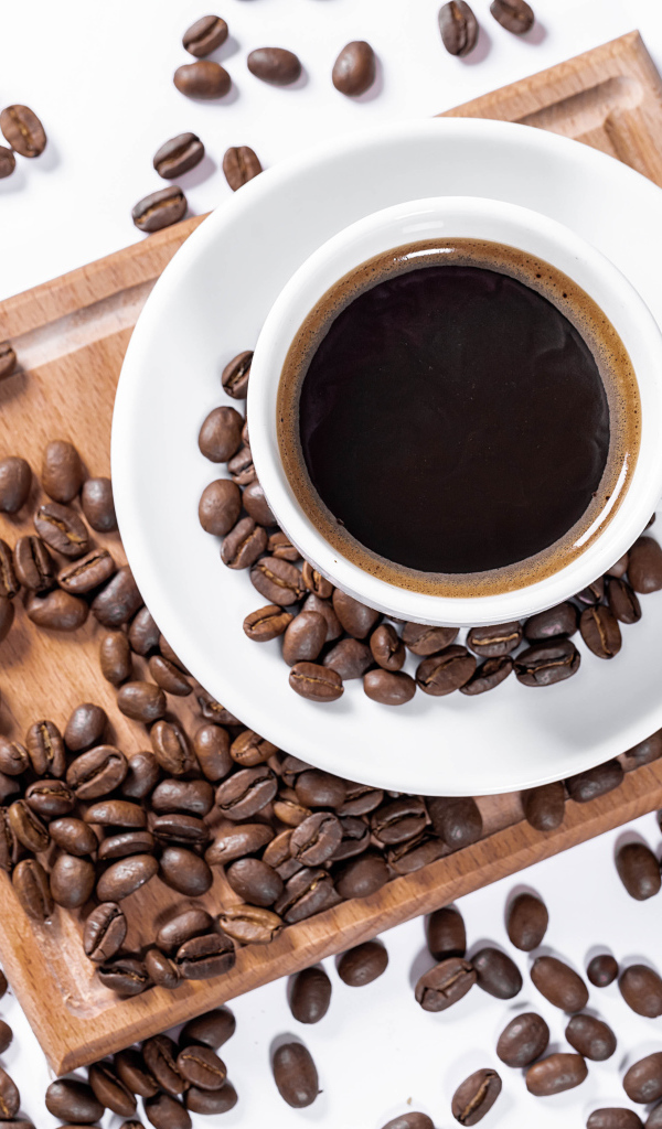 Белая чашка кофе на доске с кофейными зернами