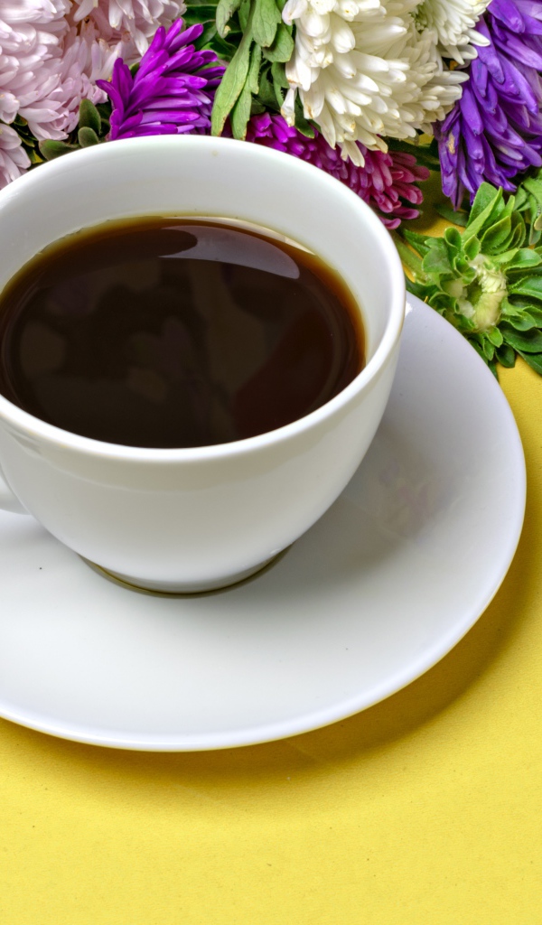 Белая чашка кофе на желтом фоне с букетом цветов астры