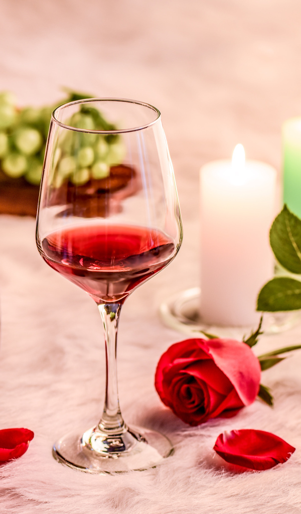 Вино на кровати с розой, виноградом и зажженными свечами