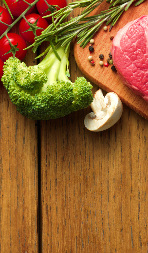 Кусок свежего мяса на столе с овощами и зеленью 