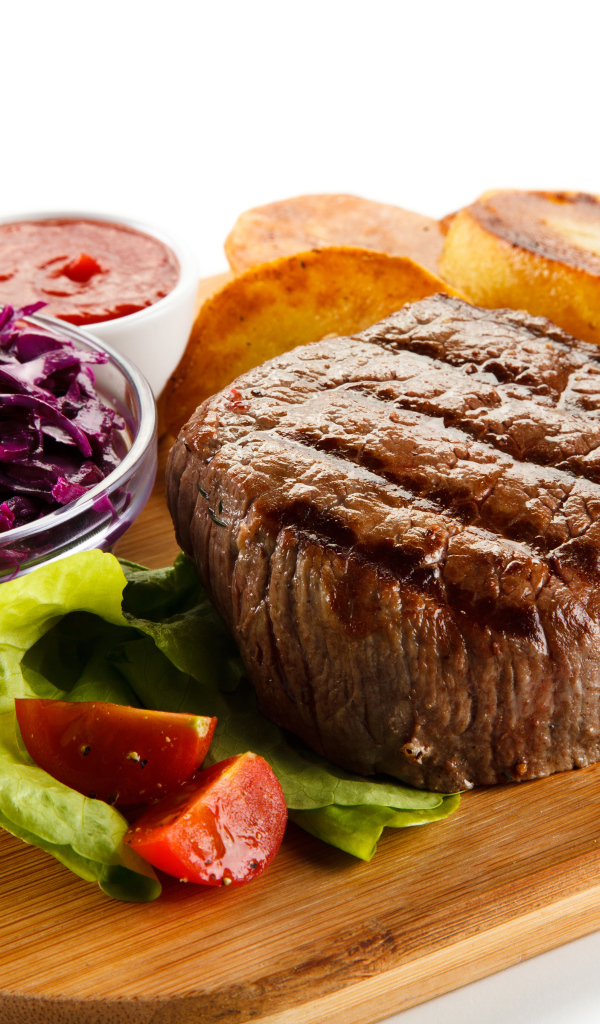 Кусок мяса гриль на доске с салатом и овощами