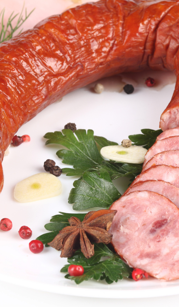 Аппетитная колбаса на белом фоне со специями и зеленью