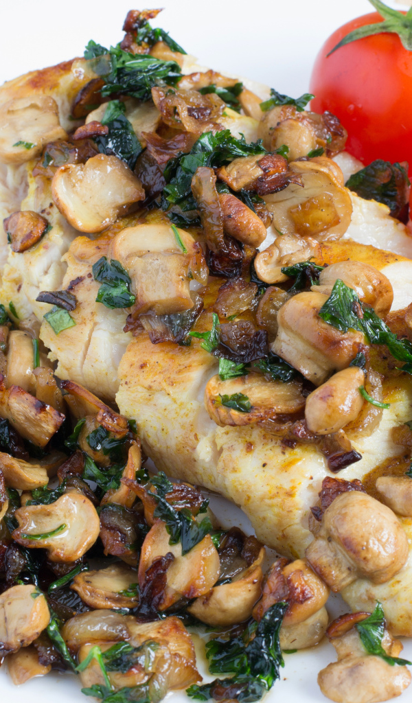 Аппетитный кусок куриного филе с грибами на тарелке с помидорами 