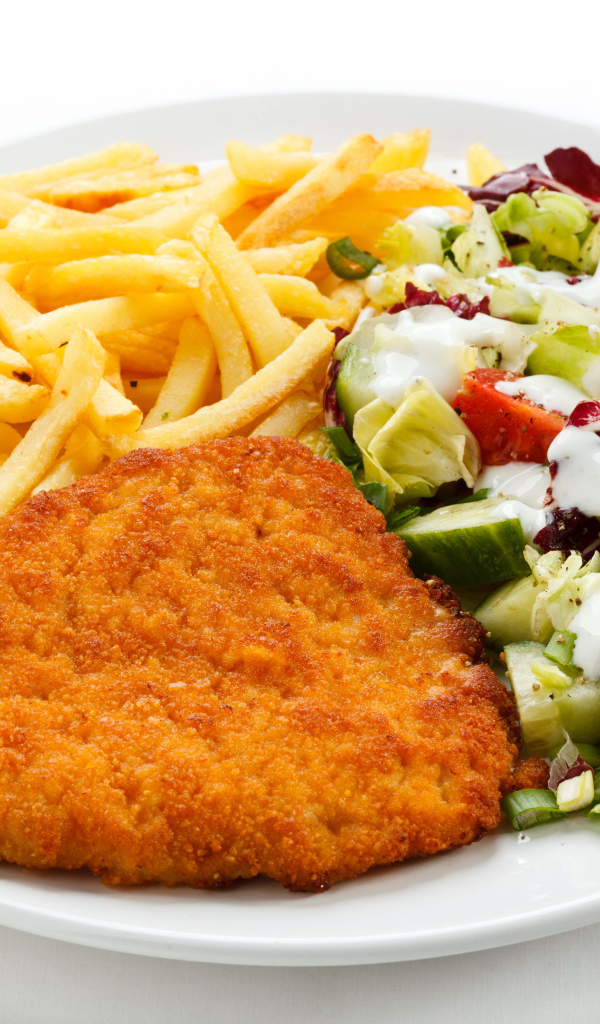 Отбивная с картофелем фри и салатом на большой белой тарелке