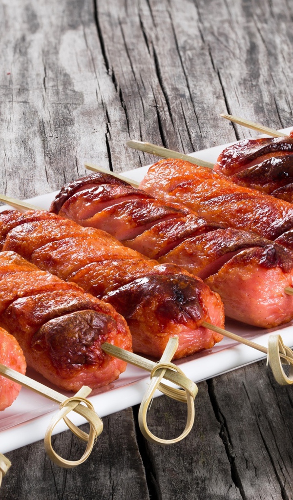 Сосиски гриль на шпажках на столе с соусом