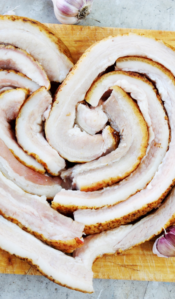 Сердце из свежего сала на доске с чесноком