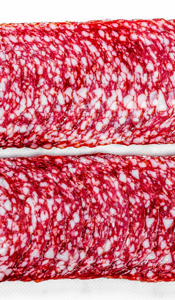 Колбаса салями нарезанная тонкими кусочками на белом фоне