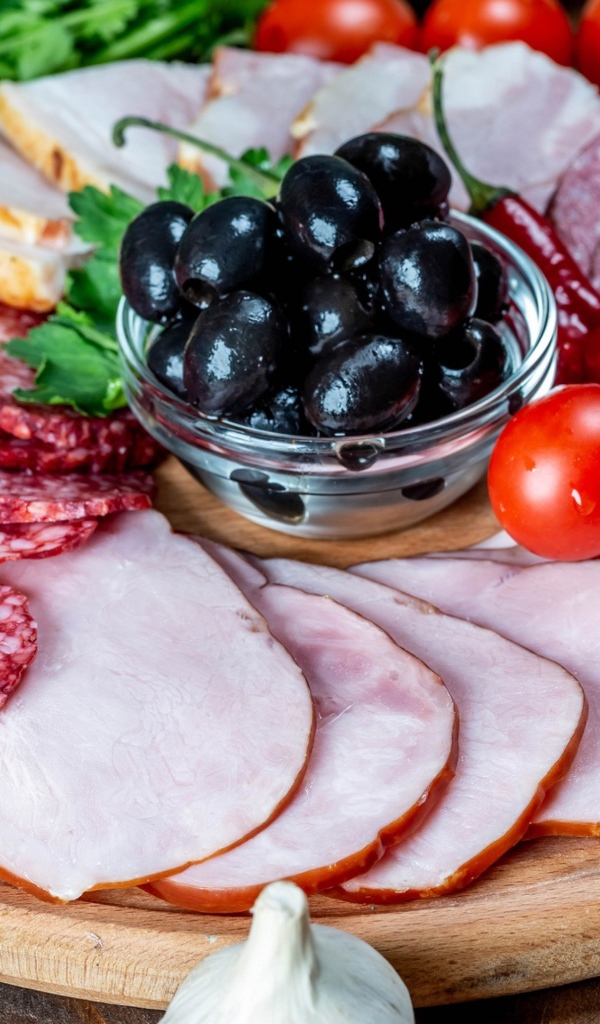 Колбасные продукты на доске с оливками