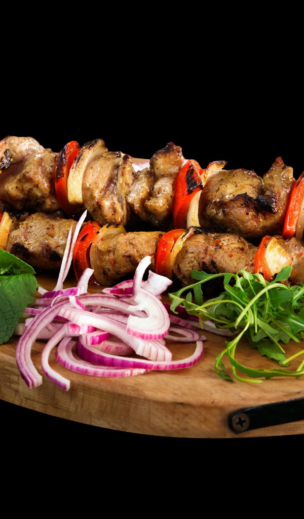 Шашлык на разделочной доске с луком и зеленью 