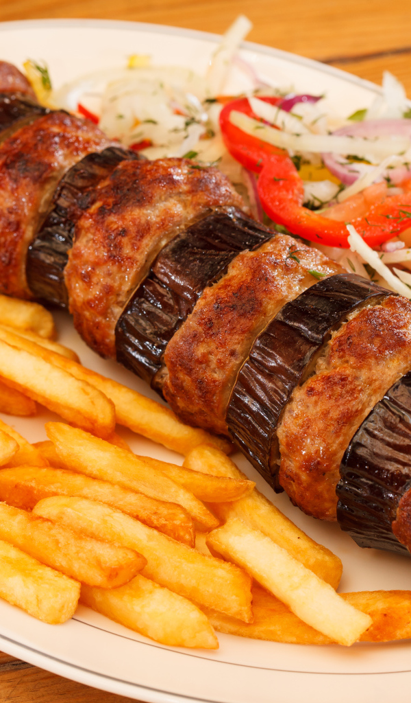 Шашлык с мясом и баклажанами на тарелке с картофелем фри 