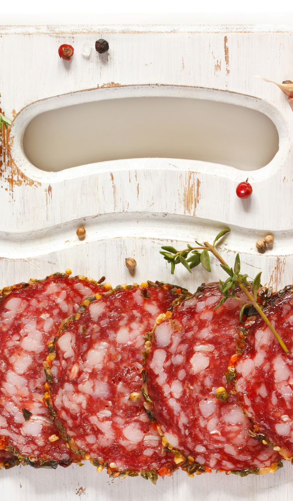 Нарезанная колбаса на разделочной доске со специями и чесноком