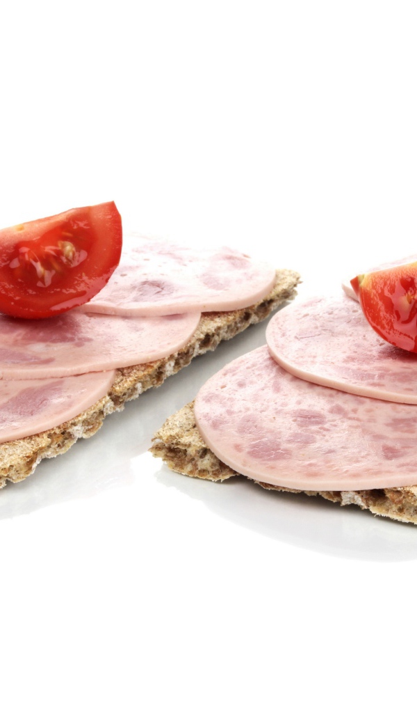 Тосты с колбасой и кусочками помидора на белом фоне