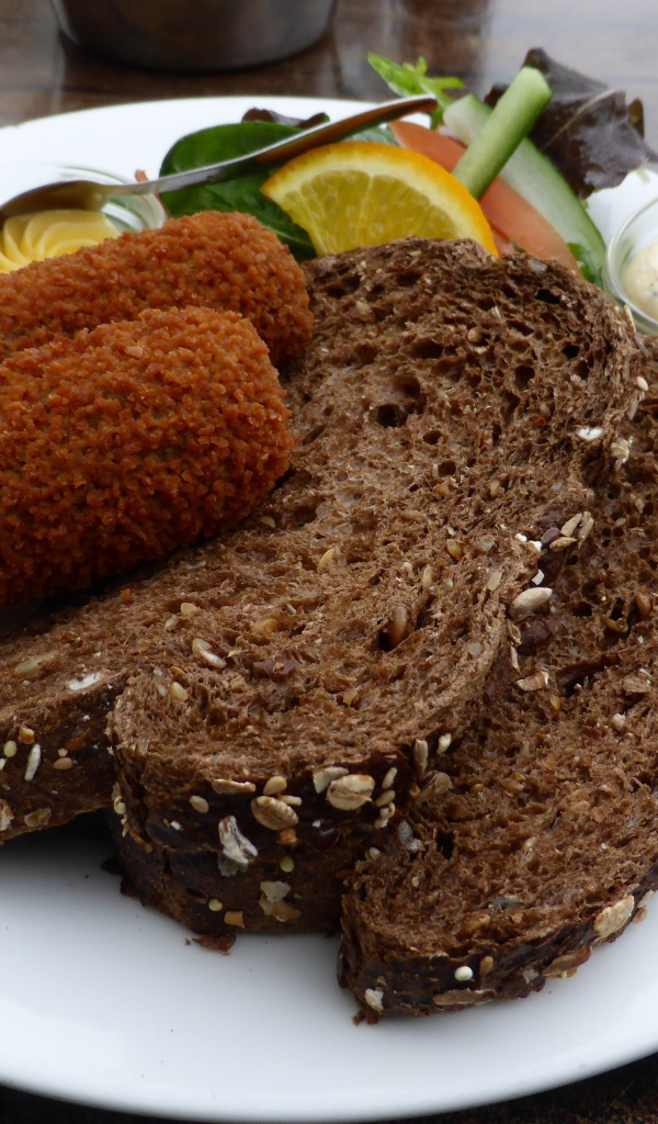 Два куска черного хлеба на тарелке с котлетами