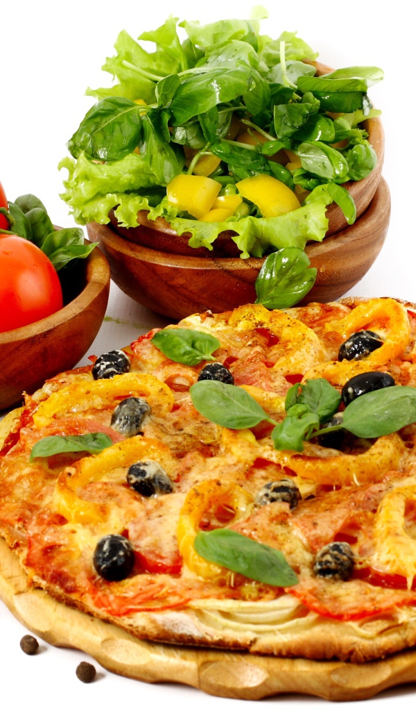 Пицца на столе с овощами и зеленью на белом фоне