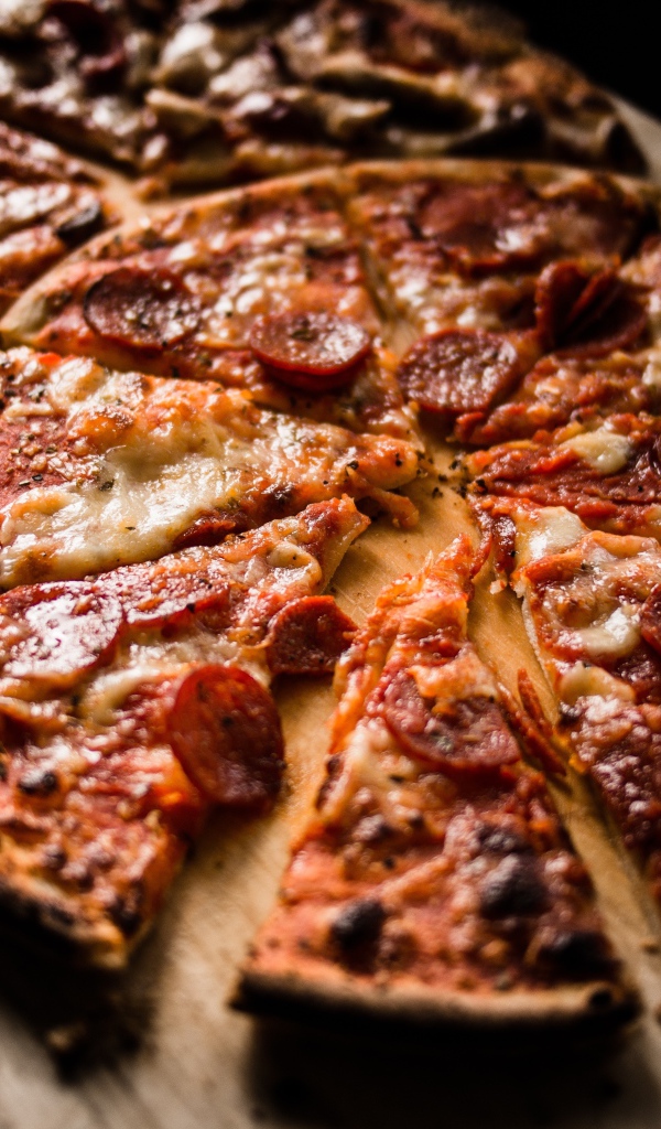 Пицца нарезана кусками на деревянной доске