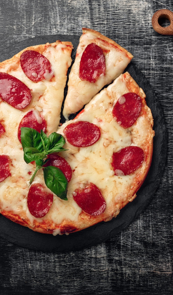 Пицца с сыром и салями на столе с помидорами и колбасой