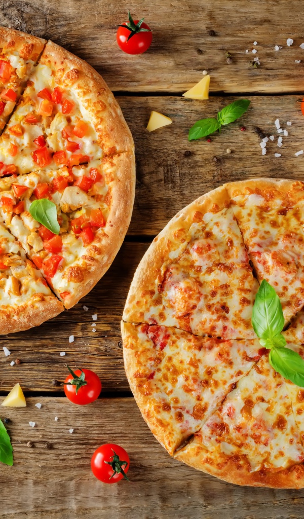 Две пиццы с сыром и болгарским перцем на столе с помидорами