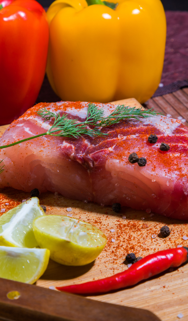 Кусок сырой рыбы на разделочной доске со специями, лимоном и болгарским перцем