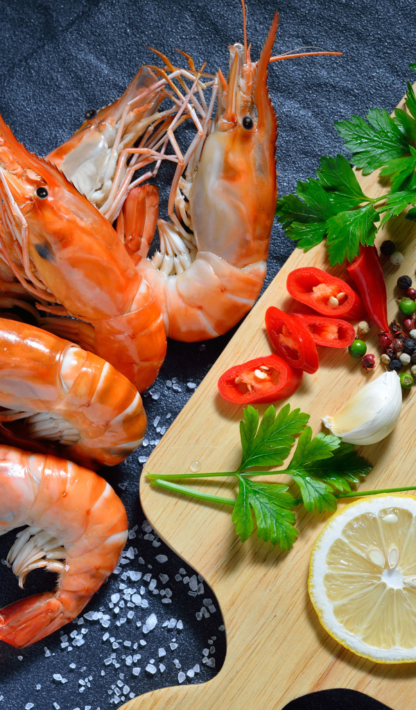 Вареные креветки на столе со специями и зеленью