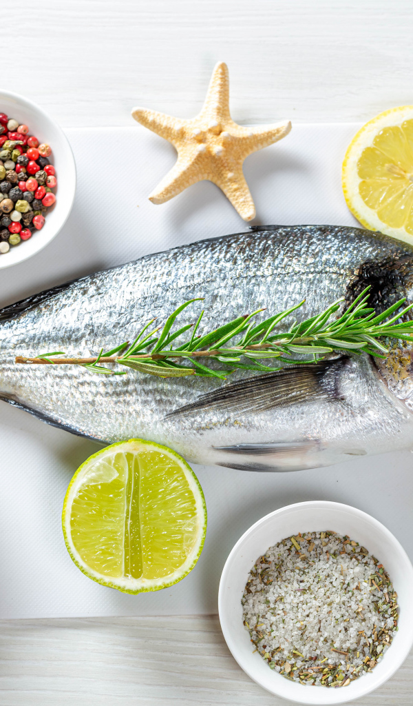 Свежая рыба на доске с солью, перцем, куркумой и лимоном