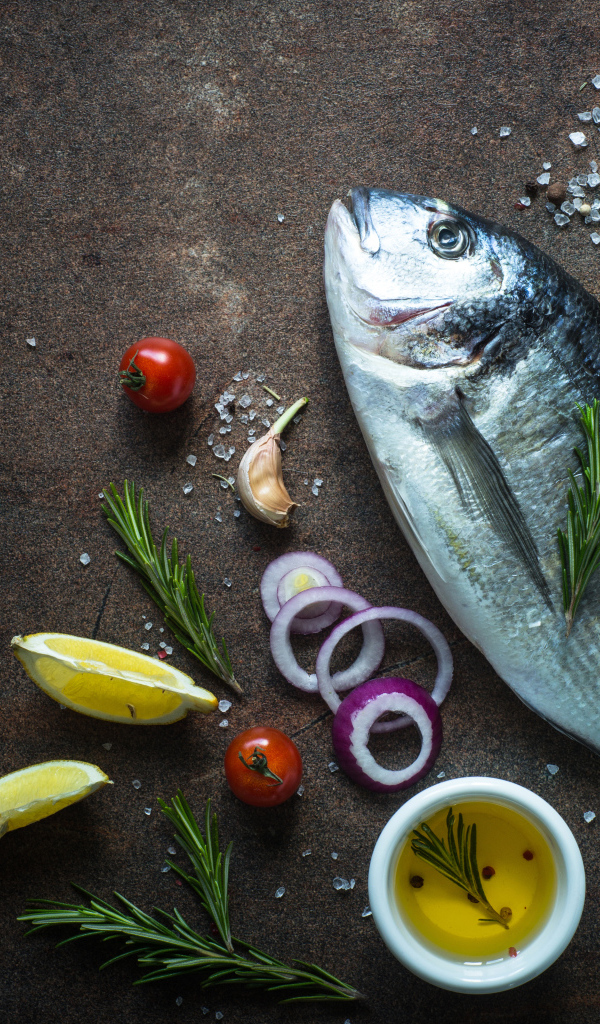 Свежая рыба на столе с овощами и специями 