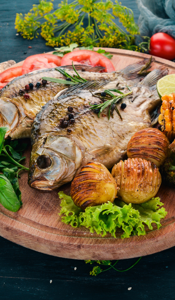 Зажаренная рыба на доске с овощами