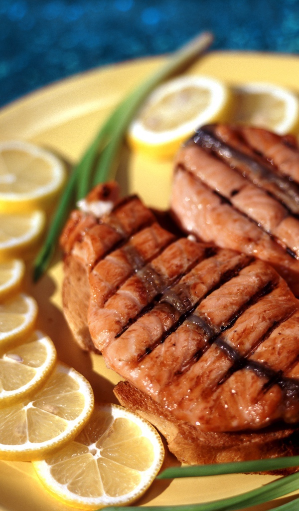 Grilled red fish with lemon slices and spring onions