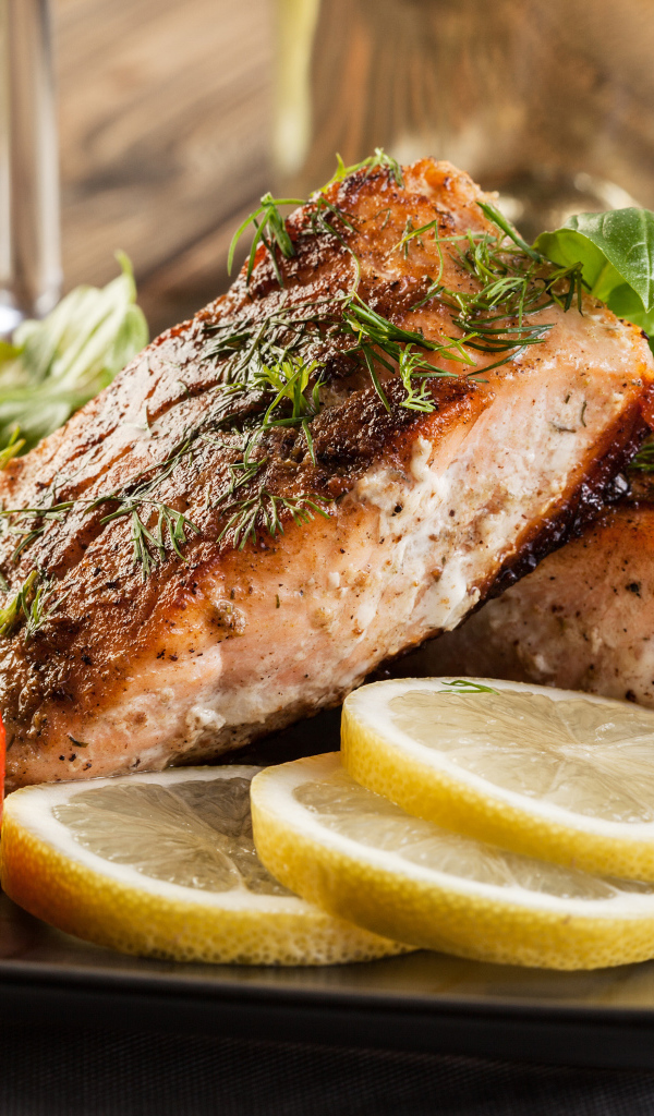 Куски запеченной рыбы на тарелке с помидорами и лимоном