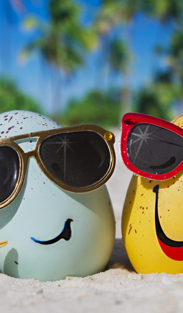 Два яйца в солнечных очках на морском песке летом