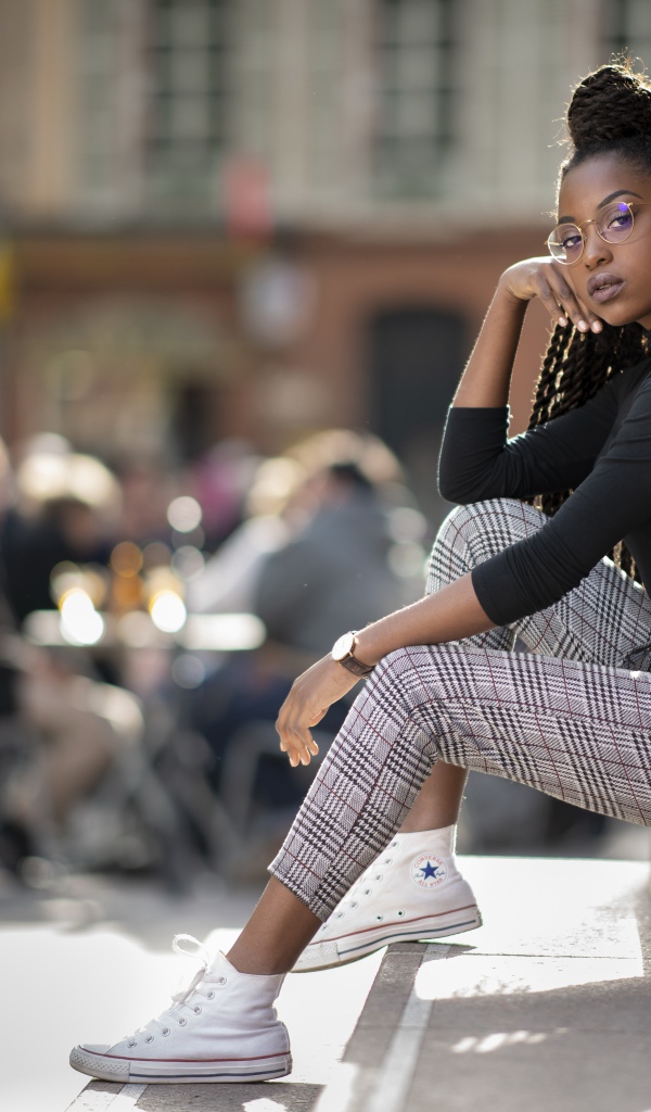 Красивая темнокожая девушка сидит на ступеньках